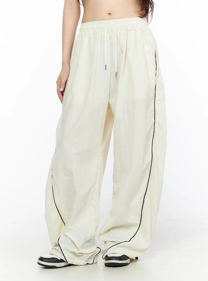 Contrast Piping Nylon Wide Pants CL523 Light beige front view on model showing drawstring waist black side piping and wide baggy nylon leg