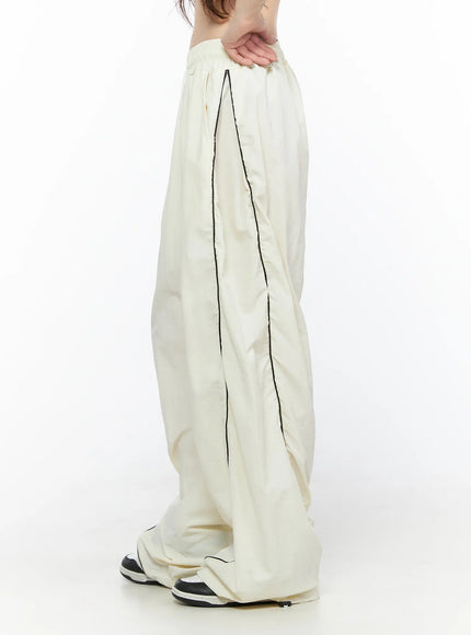 Contrast Piping Nylon Wide Pants CL523 Light beige side view on model showing black contrast piping seam and wide-leg nylon silhouette