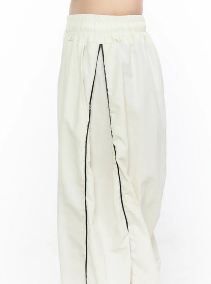 Contrast Piping Nylon Wide Pants CL523 Light beige close-up detail of elastic waistband black contrast piping and side seam nylon texture