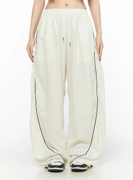 LEWKIN Contrast Piping Nylon Wide Pants CL523 Light beige front view on model wearing cropped top with drawstring waist and black piping detail