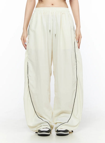 LEWKIN Contrast Piping Nylon Wide Pants CL523 Light beige front view on model wearing cropped top with drawstring waist and black piping detail