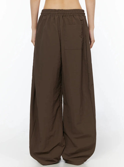 Contrast Stripe Track Pants IL509 Brown full-length back shot on model in pink halter top showing back elastic waist and oversized wide-leg pooling hem