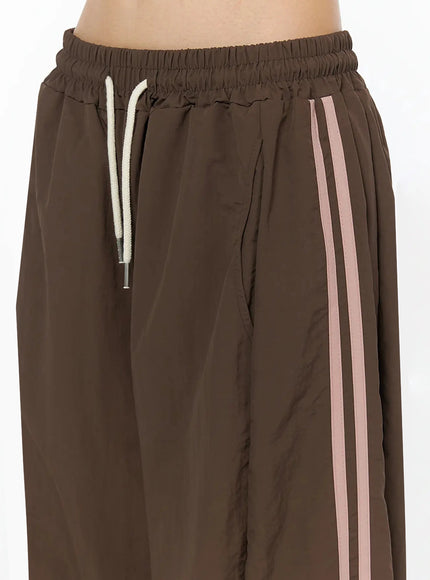 Contrast Stripe Track Pants IL509 Brown close-up back waistband detail showing elastic waist construction and patch pocket on wide-leg nylon pants