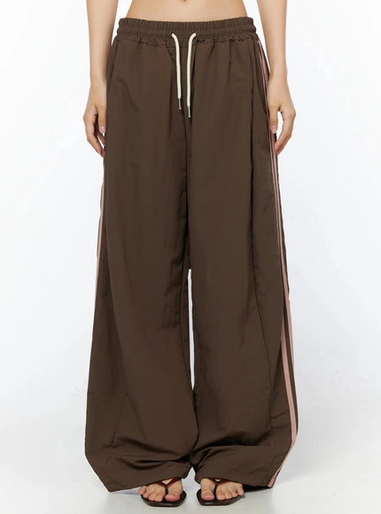 Contrast Stripe Track Pants IL509 Brown front waist-to-hem shot on model showing drawstring waistband and dual pink side stripe detail, wide-leg cut