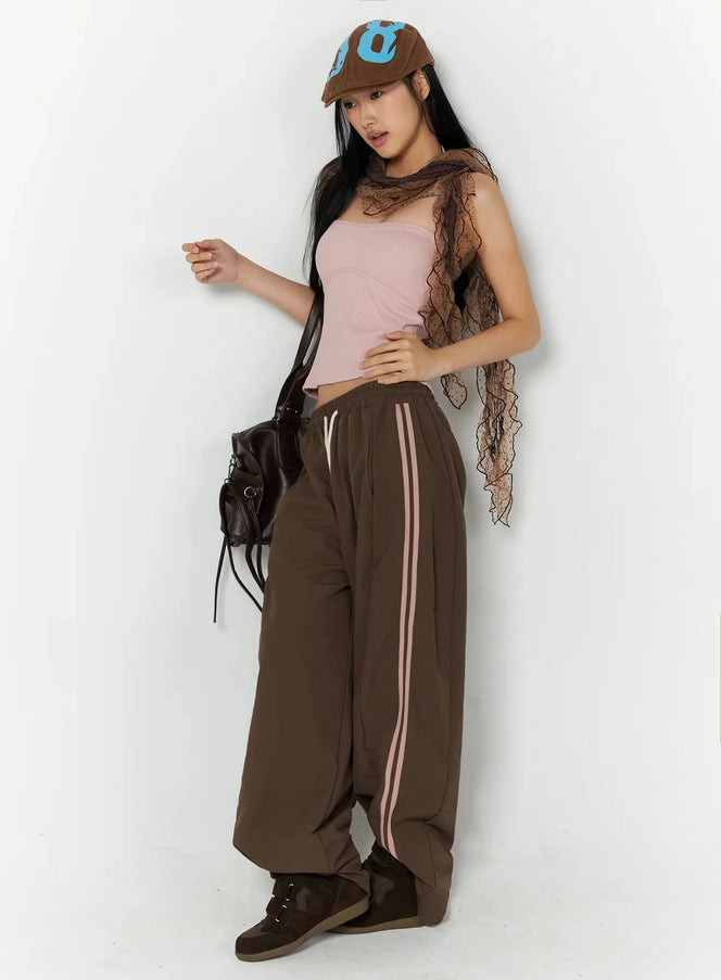 Contrast Stripe Track Pants IL509 Brown side-angle styled shot on model wearing brown cap, pink halter top and lace scarf with leather bag