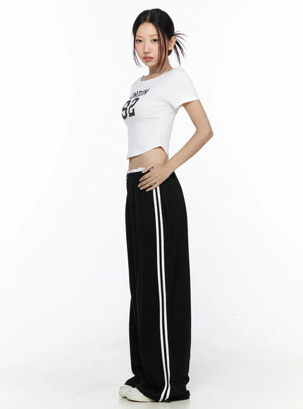 Contrast Stripe Wide Leg Sweatpants CL524 Black side full-body shot on model in white graphic crop tee hand on hip showing white double side stripe and relaxed wide-leg fit