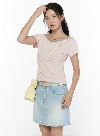LEWKIN Contrast Trim Boat Neck Tee CL521 Light pink three-quarter front shot on model hand raised to hair styled with denim mini skirt and yellow crossbody bag