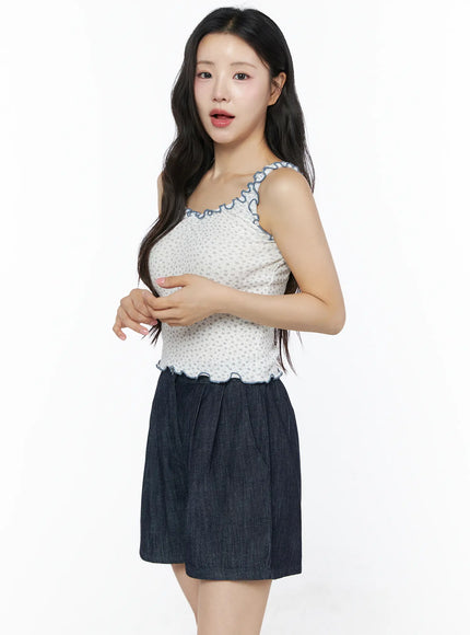 Contrast Trim Floral Tank Top IU525 Light beige side model shot three-quarter view showing blue ruffle trim neckline straps and scalloped hem with denim shorts