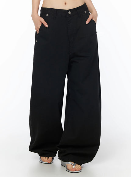 Cotton Balloon Pants IL502 Black front cropped model shot, both hands in pockets, wide-leg cotton fabric with silver rivet hardware at front pockets