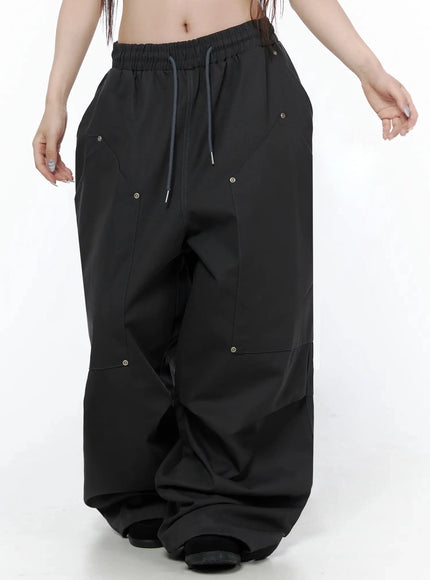 Cotton Carpenter Wide Pants IL502 Dark gray front view on model showing wide balloon leg silhouette with multi-panel seams and eyelets