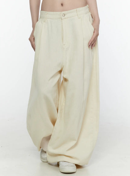 Cotton Wide Leg Pants IL521 Light beige front three-quarter view on model with hands in pockets, showcasing oversized pleated leg volume and denim fabric texture