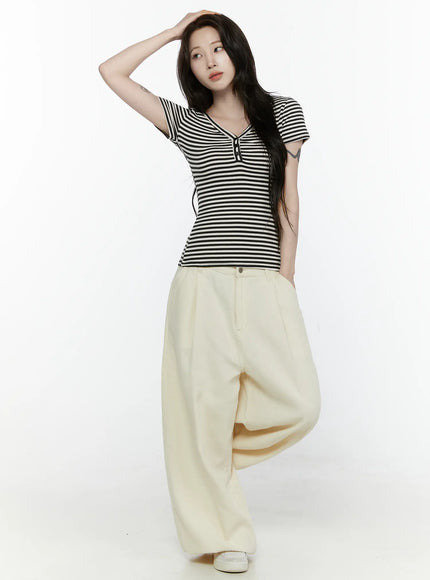 Cotton Wide Leg Pants IL521 Light beige three-quarter front view on model with hand on head, wide balloon leg drape, styled with striped top and sneakers
