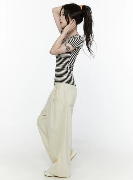 Cotton Wide Leg Pants IL521 Light beige side view on model with arms raised in ponytail pose, showing voluminous wide-leg silhouette and side pocket detail