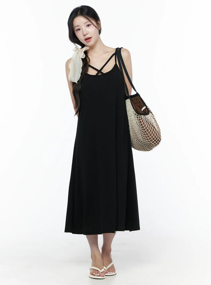 Criss-Cross Strap Maxi Dress IU525 Black styled front view on model with braided hair, ivory ribbon hair tie, carrying woven mesh tote bag and white sandals