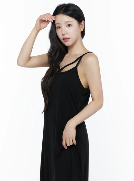 Criss-Cross Strap Maxi Dress IU525 Black side-angle close-up on model raising hand to hair, showing cross-strap neckline and relaxed drape of soft fabric