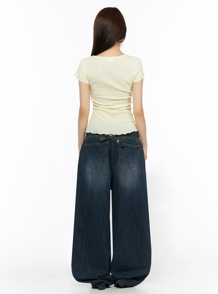 Cruz Wide Leg Jeans IL523 Dark blue back view on model, styled with yellow graphic tee, showing crossover snap tab at waistband, two back pockets, wide pooling hem