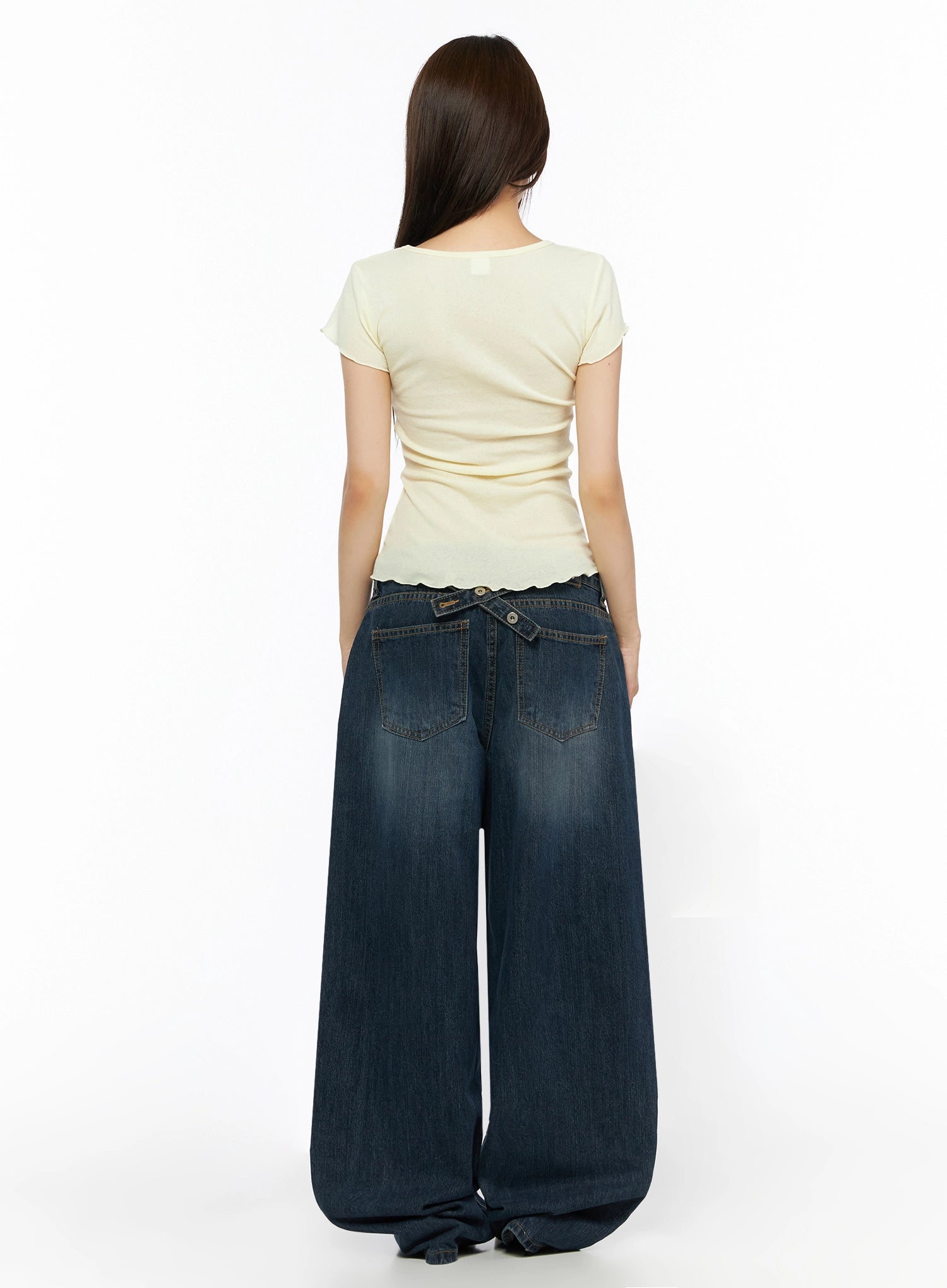 Cruz Wide Leg Jeans IL523 Dark blue back view on model, styled with yellow graphic tee, showing crossover snap tab at waistband, two back pockets, wide pooling hem