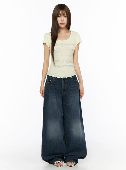 Cruz Wide Leg Jeans IL523 Dark blue full-body front view on model, styled with yellow graphic tee, standing straight, ultra-wide leg hem pooling at floor, sandals