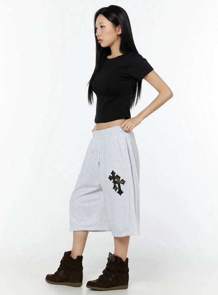 Curved Hem Baby Tee IL516 Black side shot on model showing slim curved hem silhouette and elastic waistband of gray shorts below