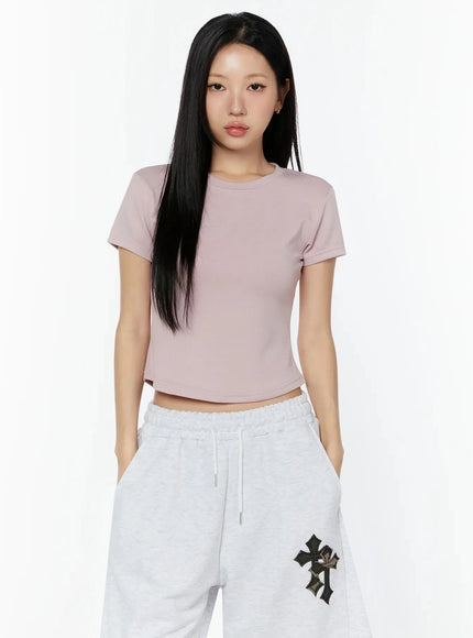 Curved Hem Baby Tee IL516 pink front shot on model showing crew neck and cropped silhouette, paired with gray cross-patch shorts