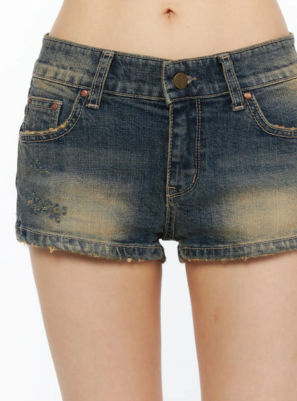 Distressed Low-Rise Denim Shorts CU530 Dark blue close-up front detail showing distressed stitching, faded wash, raw hem and copper rivets