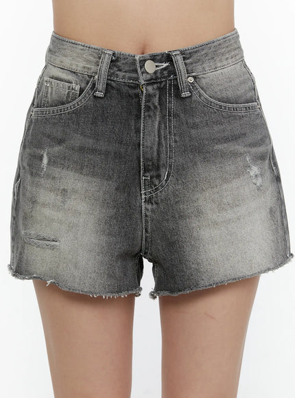 Distressed Mini Denim Shorts CL507 Black close-up front detail on model showing acid-wash texture, distressed rips, silver button, and frayed cutoff hem