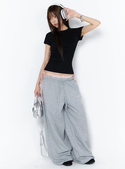 Dot Print Sagging Sweatpants IL515 Gray full-body angled shot on model wearing headphones and silver bag styled with black crop tee