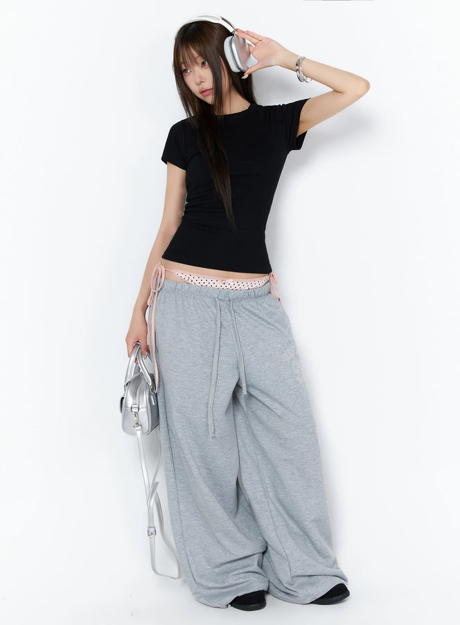 Dot Print Sagging Sweatpants IL515 Gray full-body angled shot on model wearing headphones and silver bag styled with black crop tee