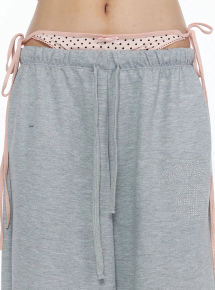 Dot Print Sagging Sweatpants IL515 Gray close-up detail of double-layered waistband with pink polka dot trim drawstring and rhinestone lettering on thigh
