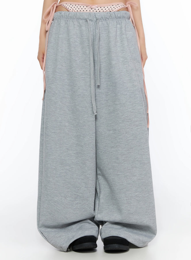 LEWKIN Dot Print Sagging Sweatpants IL515 Gray front close-up on model showing pink polka dot layered waistband with drawstring and rhinestone logo detail