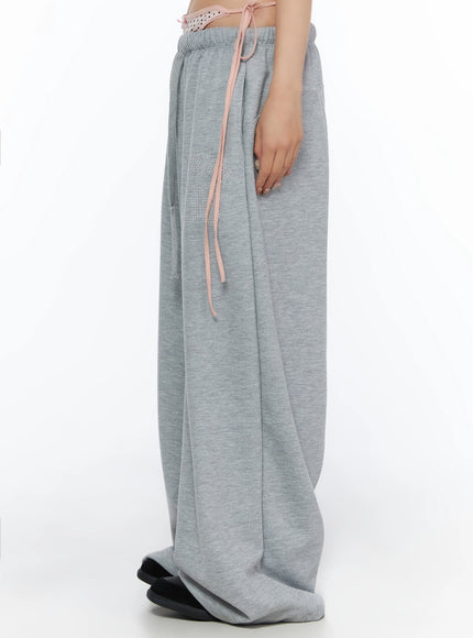 Dot Print Sagging Sweatpants IL515 Gray side cropped shot on model showing deep wide-leg silhouette rhinestone thigh logo and pink ribbon drawstring detail