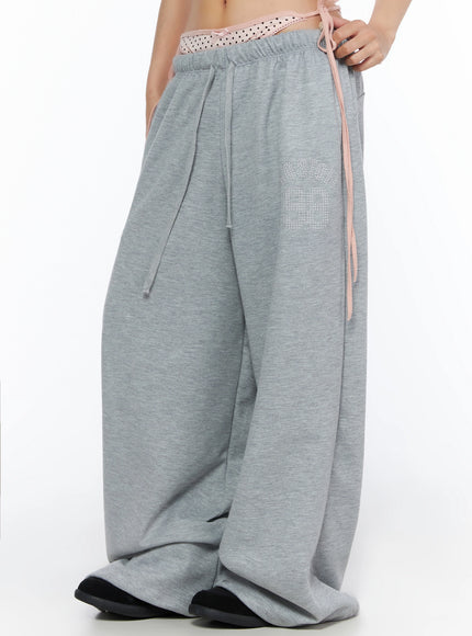 Dot Print Sagging Sweatpants IL515 Gray side close-up on model showing rhinestone logo pink side ribbon tie and wide-leg silhouette with elastic waistband