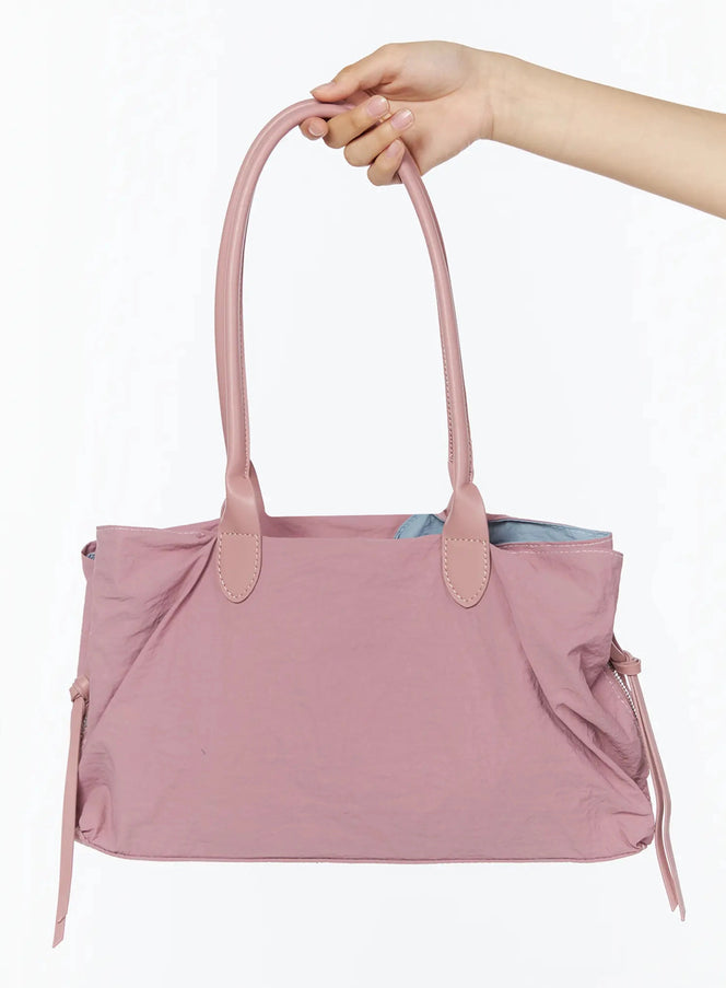 LEWKIN Double Pocket Shoulder Bag IL516 Pink front view held by model's hand showing nylon body dual top handles leather tab stitching and side drawstring ties