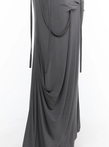 Draped Maxi Skirt CL503 Dark gray close-up detail of curved pocket, long dangling ties, and draped lower skirt fabric on hanger-style shot