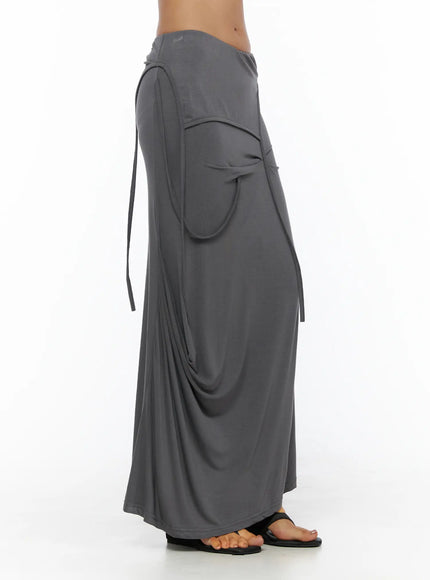 Draped Maxi Skirt CL503 Dark gray side view on model displaying oversized curved pocket, dangling tie straps, and fluid jersey silhouette