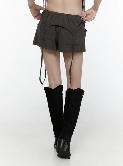 Drawstring Banded Shorts IL522 Dark gray back view on model showing dual back pockets, elastic waistband, and long dangling straps falling down legs with black boots