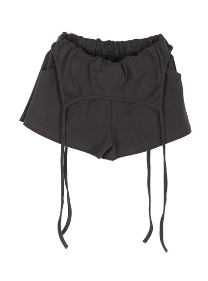 Drawstring Banded Shorts IL522 Dark gray flat-lay front showing elastic waistband, curved arc seam, layered skort silhouette, and four long fabric drawstrings