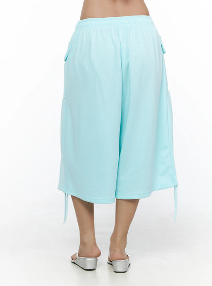 Drawstring Bermuda Shorts CL513 Mint back shot on model showing smooth elastic waistband, wide-leg cut, side flap pockets, and hem drawstring ties with silver sandals