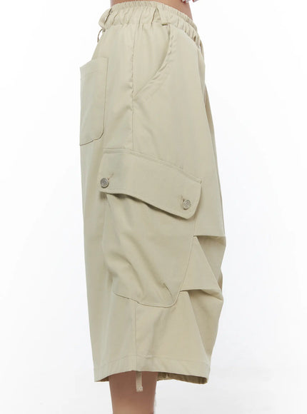 Drawstring Cargo Jorts CL510 Beige side shot on model highlighting snap-button flap cargo pocket, side seam detail, and voluminous layered hem