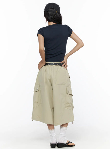 Drawstring Cargo Jorts CL510 Beige back full-body shot on model styled with navy crop tee, studded belt, and cap with hands on hips