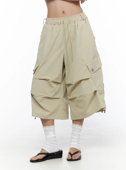 Drawstring Cargo Jorts CL510 Beige angled front shot on model showing drawstring waist, layered wide-leg panels, and snap cargo pockets with white lace socks
