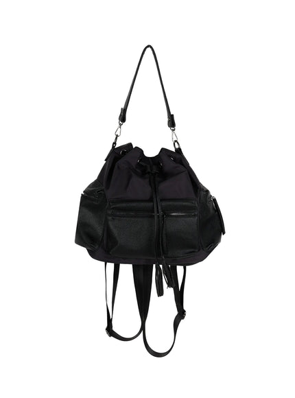 Drawstring Pocket Bucket Bag IL515 Black front product shot on white background showing dual zip pockets, nylon upper, pebbled leather lower, long shoulder strap, and tassel