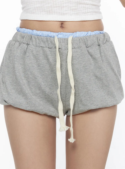 Drawstring Sweat Shorts CL527 Gray close-up detail shot on model highlighting cream rope drawstring, double-layer blue elastic waistband, and fleece fabric texture