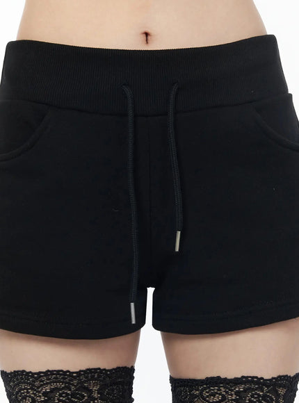 Drawstring Sweat Shorts IL502 Black close-up front detail showing ribbed elastic waistband, drawstring with metal tips and side pockets on model