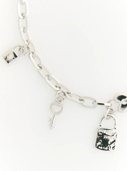 Eden Key Bracelet IL522 silver detail flat lay showing padlock and heart key charms with mixed oval and cable chain links on white