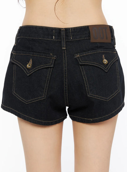 Eimi Low-Rise Denim Shorts CU530 Dark blue close-up back shot on model showing dual flap pockets with snap buttons, contrast stitching and leather brand patch at waistband