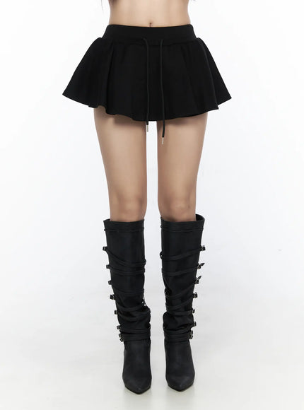 Elastic Waist Tiered Ruffle Mini Skirt CL524 Black front full-length shot on model, skirt with flared pleated hem and drawstring waist, styled with black multi-buckle heeled knee boots