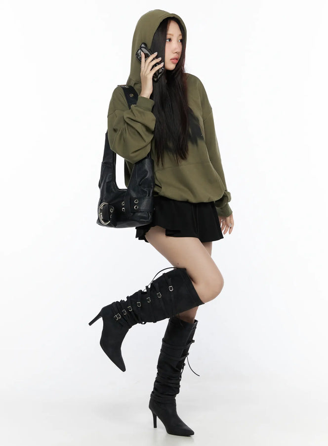 Elastic Waist Tiered Ruffle Mini Skirt CL524 Black full-body side shot on model wearing green graphic hoodie, black mini skirt, and black buckle tall boots, holding phone