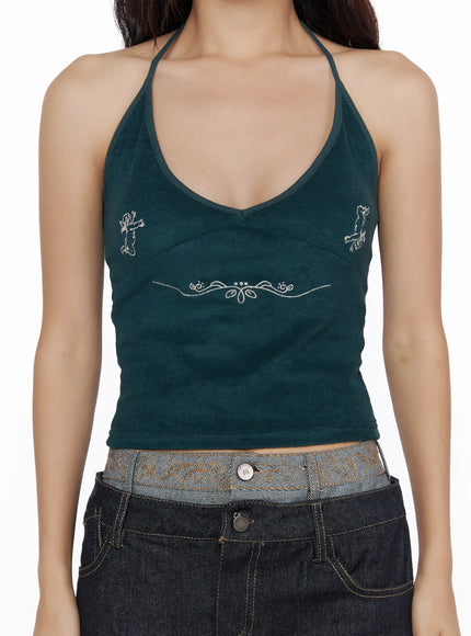Embroidered Halter Top CL513 Dark green close-up front model torso shot V-neck halter silver angel motif and floral scroll embroidery on ribbed dark green fabric