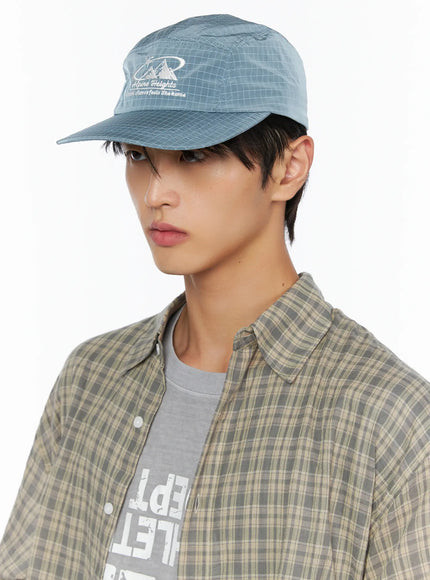 Embroidered Outdoor Cap IL520 Blue close-up front three-quarter model shot showing Alpine Heights embroidery on grid-texture ripstop nylon panel